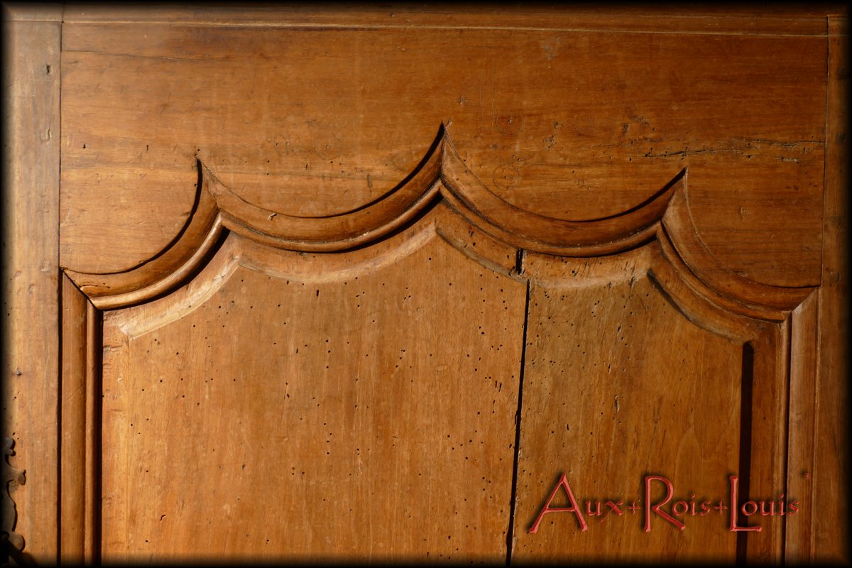 Sur la porte un motif à trois pointes évoque une couronne royale, mise en valeur sur la veine du noyer blond.