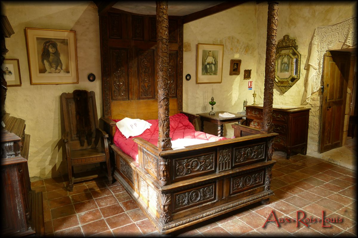 Au centre trône un lit à colonnes du XVIIᵉ siècle à côté duquel les effets personnels sont remisés dans une charmante commode Louis XV.