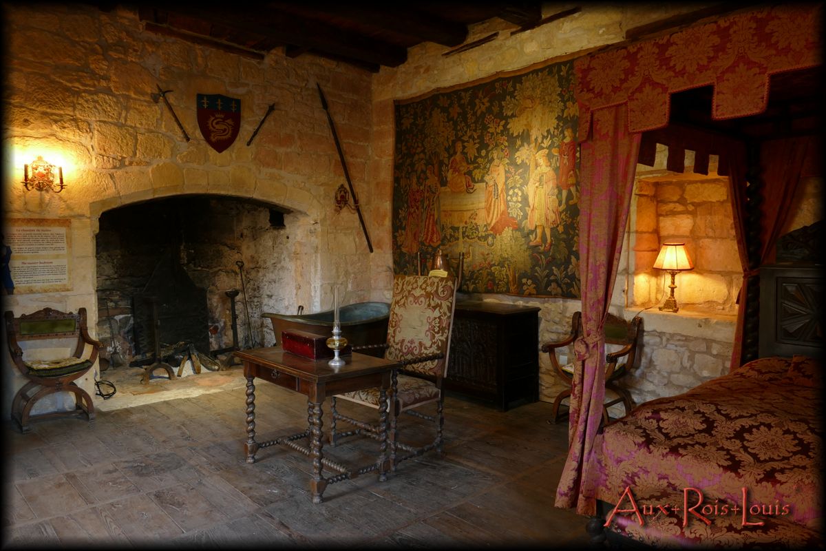 On the first floor of the Keep, the Lord's bedroom with a huge fireplace has a small Louis XIII table in the center behind which we notice a Gothic chest.