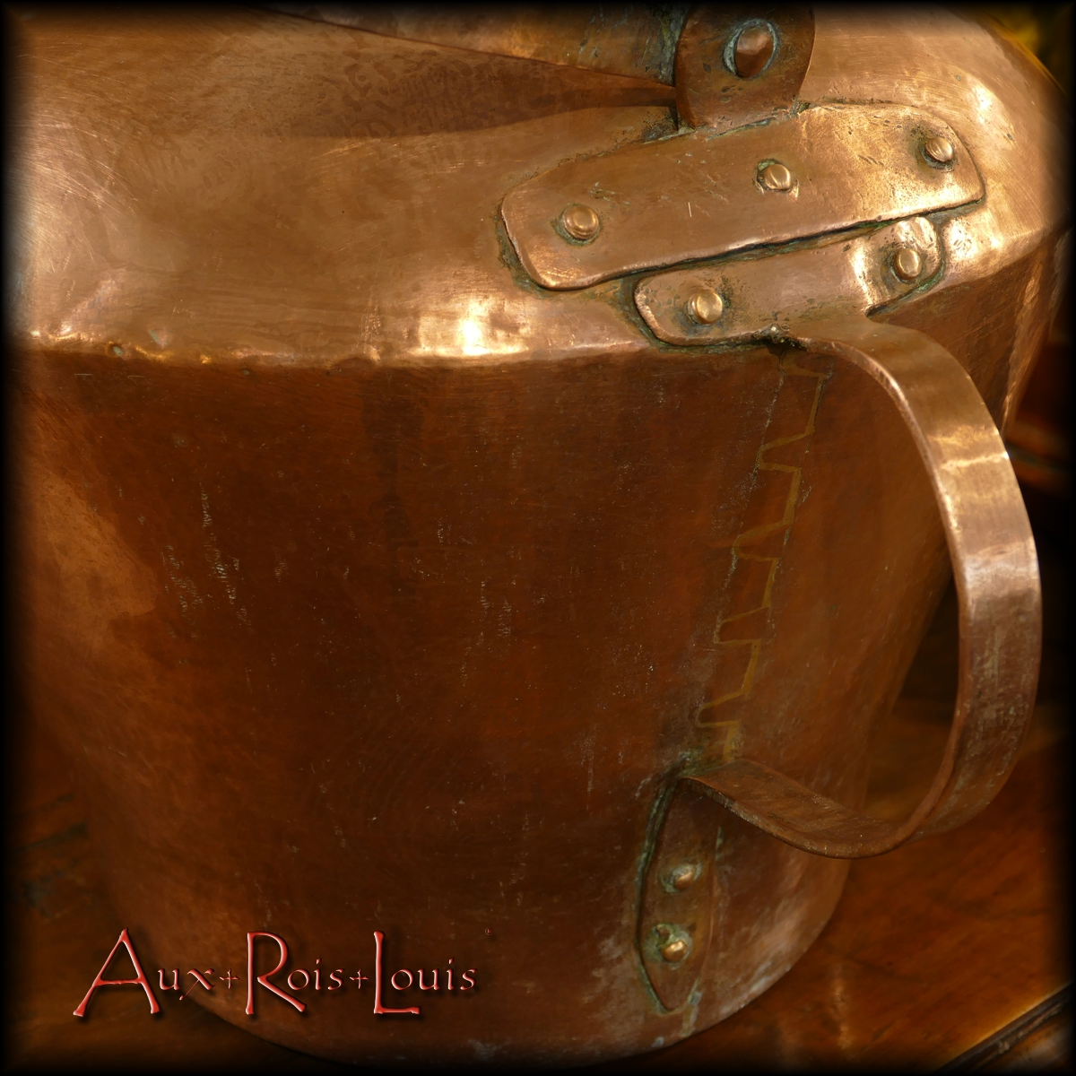 We can see under the handle of a large red copper kettle from the 18th century, the way its belly has been welded. Slotted "straight tails" were cut from either side of a hammered sheet of copper, then soldered face to face with hot brass.
