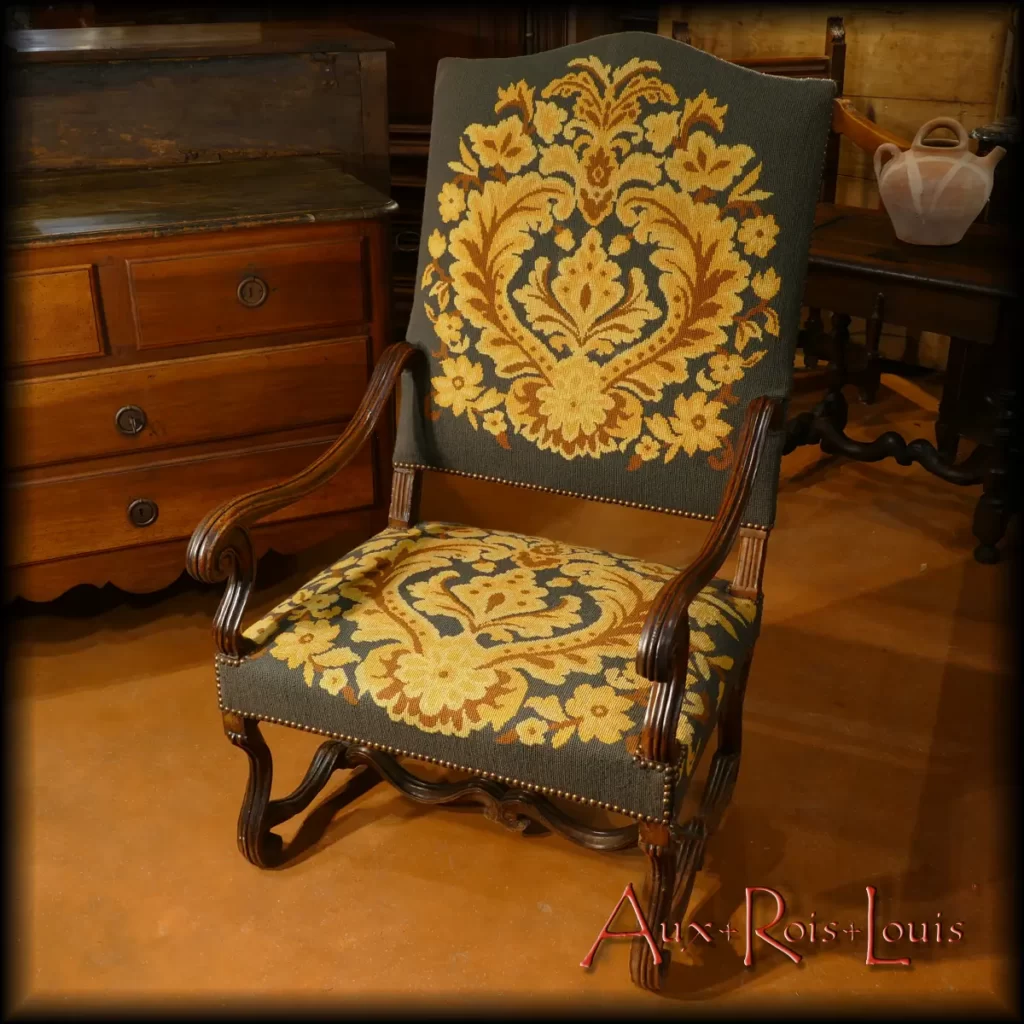 Ce large fauteuil tapissé, idéal pour se blottir et palabrer au coin du feu, est né dans une noble demeure de l’Aveyron au XVIIᵉ siècle. Ses pieds et traverses de forme arrondie présentent des ondulations sinueuses typiques du motif en « os de mouton ». Sous Louis XIV les structures des sièges en bois ciré épousent volontiers cette forme caractéristique très chic.