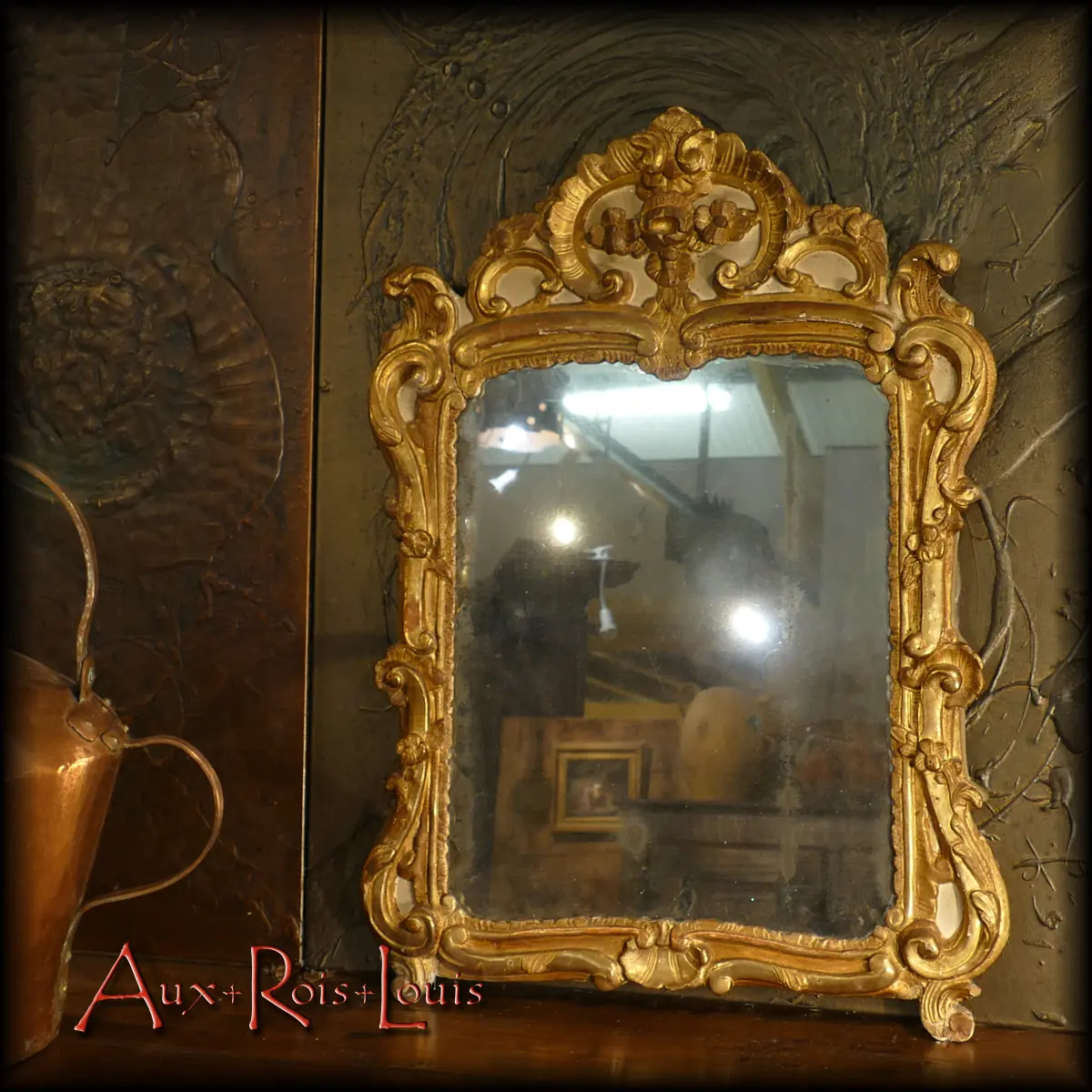 Curves, volutes, and Saint-Jacques shells – everything exudes the essence of Provence and the pure Louis XV style in this gilded wooden rococo mirror, resting upon two elegant feet. It dates back to the 18th century and has reached us in a remarkably preserved condition. Its mercury glass and wooden frame adorned with gold leaf gilding in the Armenian style are original.