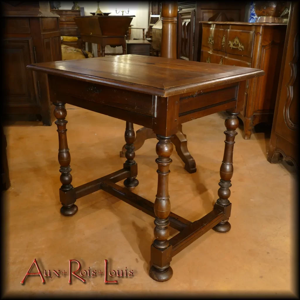 Here is a small cherry wood salon table commissioned by a castle in Périgord in the 18th century. It follows the codes of the Louis XIV style, featuring a moulded balustrade base connected by an H-shaped stretcher and blackened mouldings on the side rails. It has a drawer that spans its entire width.