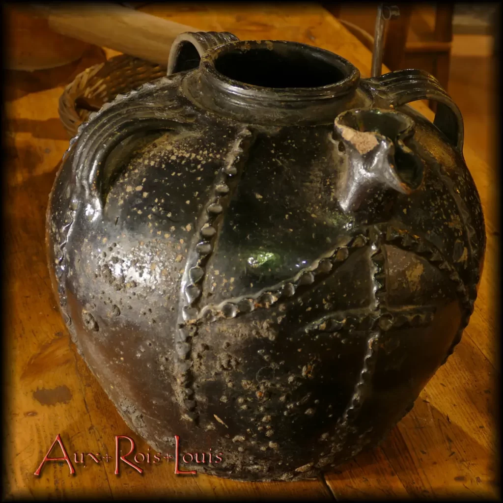 This globular mélard with pinched spout, an intermediary size between the large mélard and the oil jug, was meant to be suspended. Its base is rounded for this purpose, to ensure the attachment of a rope without sharp angles. The rope passing under the bottom was held from bottom to top against the pottery's belly by another transverse rope passing under the specially flared neck. The whole was suspended from a beam resembling a joist. This mélard is covered with a green glaze and a lead cover, two finishes intended to provide it with brilliance and waterproofing. Its decoration consists of finger-molded bands. The facade is adorned with a cross motif placed under the pinched spout. This reduced spout allowed for a faster, smoother flow.