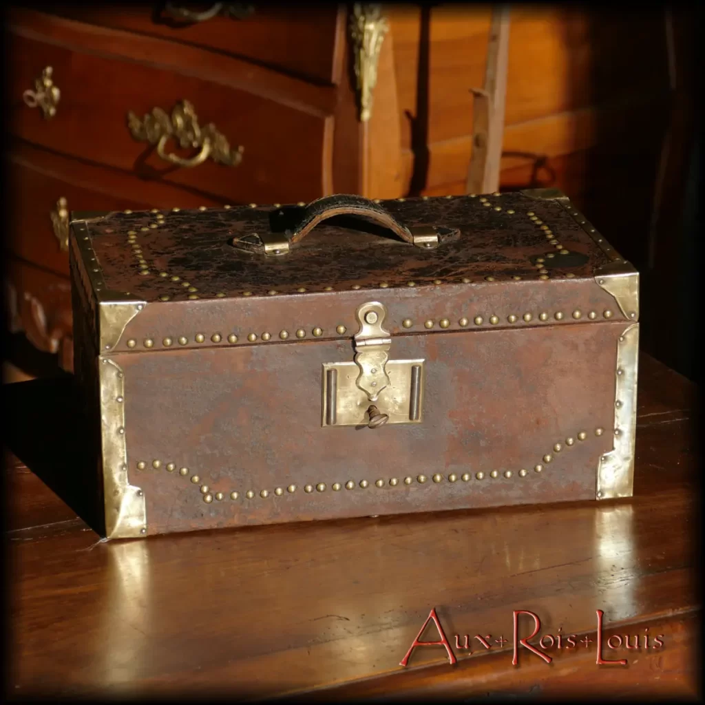 This 18th-century coach chest is clad in leather on the outside and bordered with studded brass. The interior is lined with hand-painted wallpaper, forming speckled patterns. Originally, this type of luggage was the work of the guild of trunk makers, a separate trade from the saddlers harness makers, emerging during the 14th century.